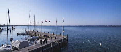 Eine Anlegestelle mit vertäuten Booten, Flaggen und freiem Blick auf das Wasser.