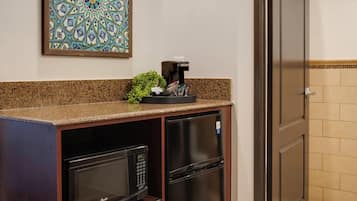 Une cuisine compacte équipée d’un four à micro-ondes, d’un réfrigérateur et d’une machine à café posée sur le plan de travail.