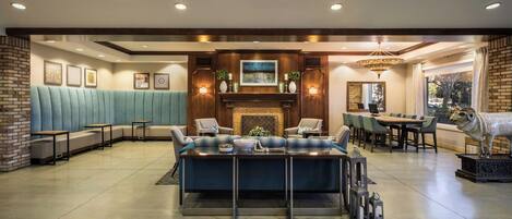 A modern lounge area with a sofa, chairs, a dining table, and a fireplace.