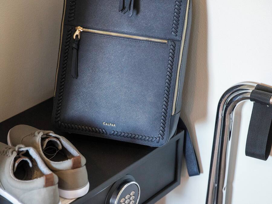 A black suitcase with a zipper and a tag, placed on a black table next to a pair of shoes.