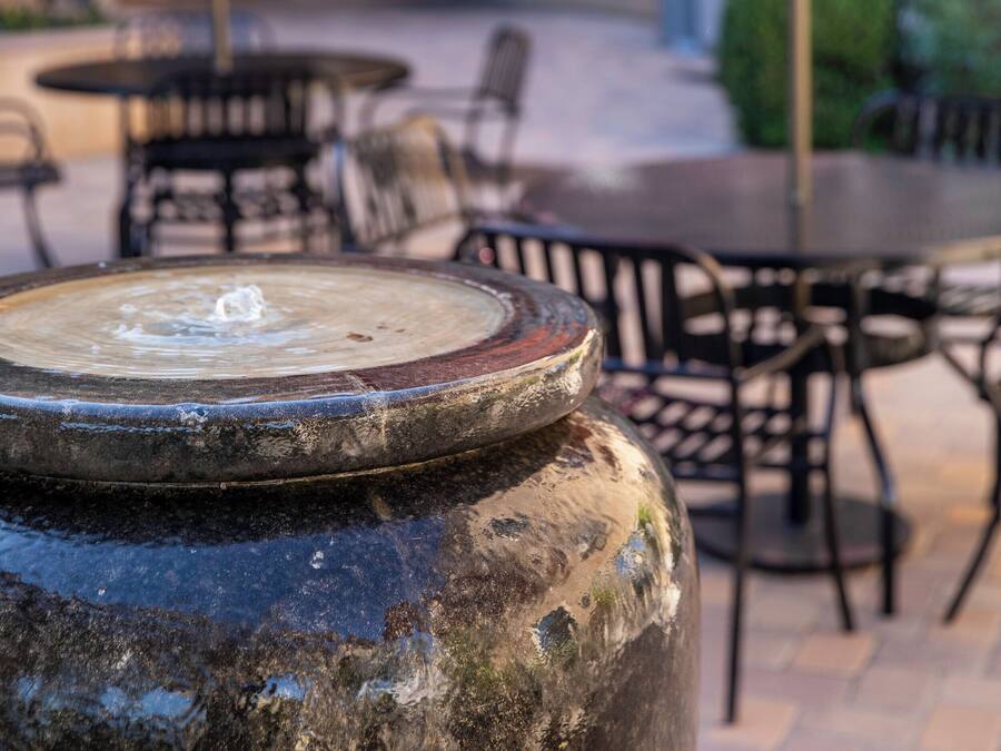 A patio area with outdoor seating, including tables and chairs, and a large decorative urn in the foreground.