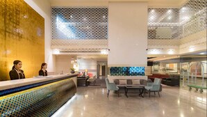Eine geräumige Lobby mit Empfangstresen, Sitzgelegenheiten und einer Wand mit geometrischem Muster.