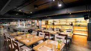 Ein Restaurant mit mehreren Tischen, Stühlen und einer Bar mit Regalen voller Flaschen.