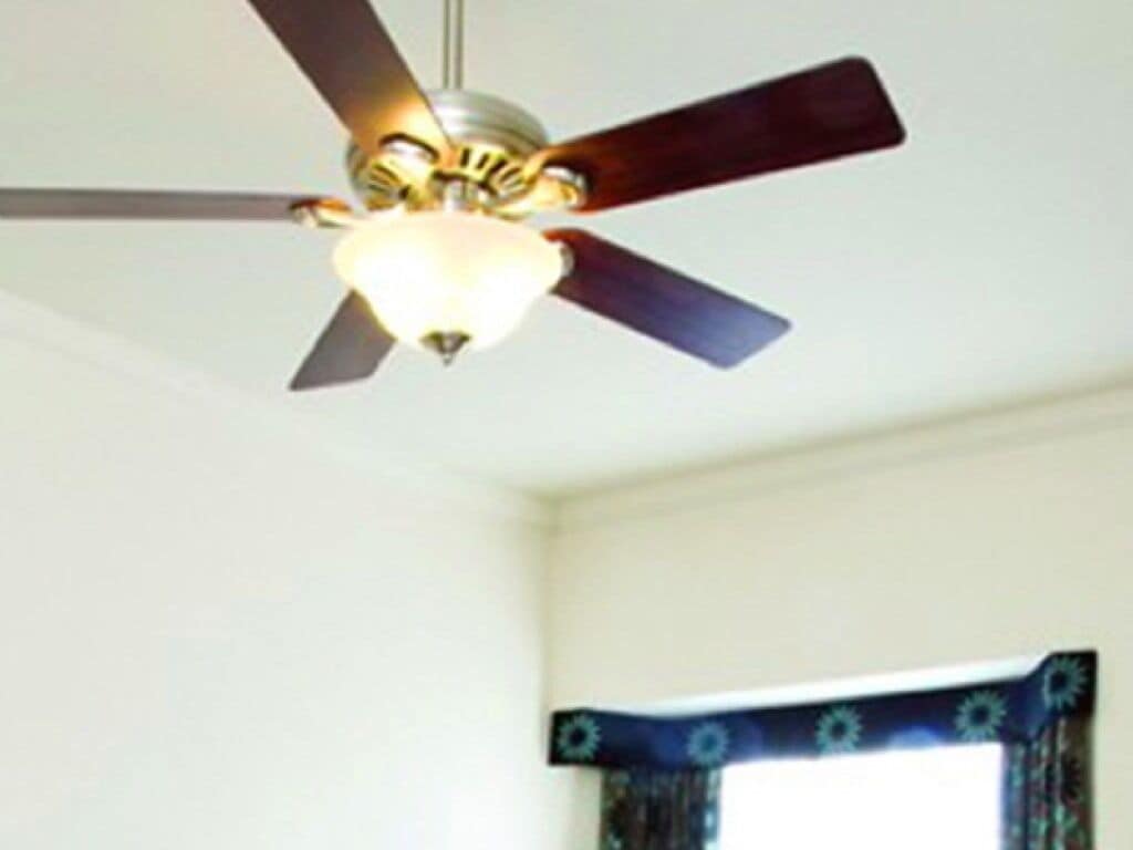 Ein Deckenventilator mit drei Flügeln und einer Lampe.