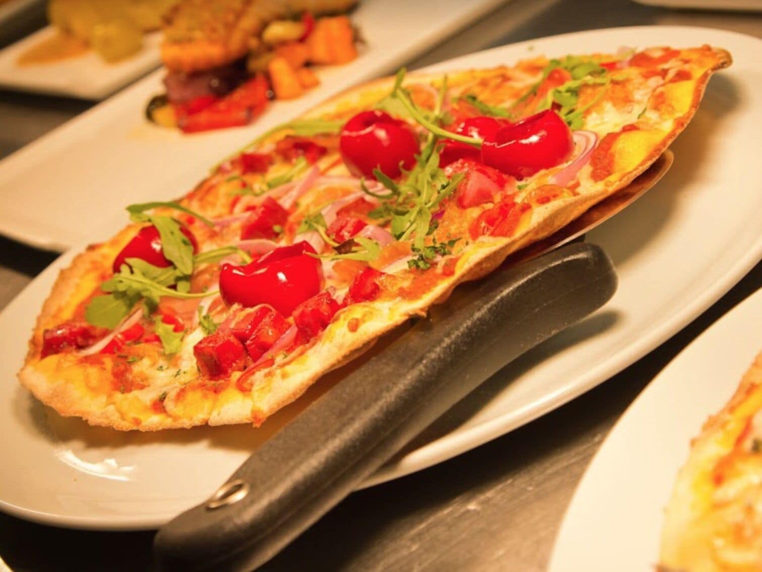 Eine Pizza mit Belag auf einem weißen Teller.