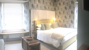 A bedroom with a bed, bedside table, and a window with blinds. - The Railway Inn (Brixham)