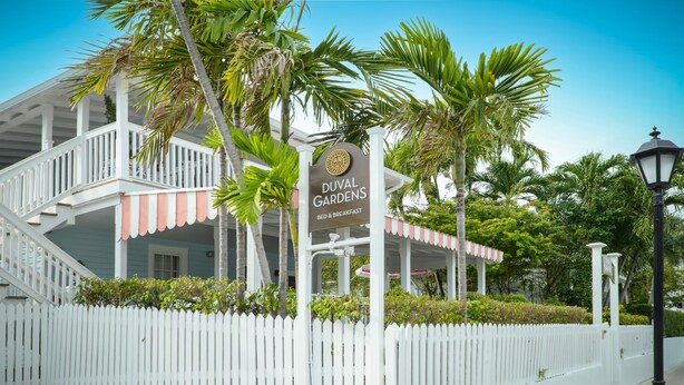A white picket fence, a sign for Duval Gardens Bed & Breakfast, and a palm tree. - Duval Gardens at Southernmost Beach Resort – Adults Only (Key West)