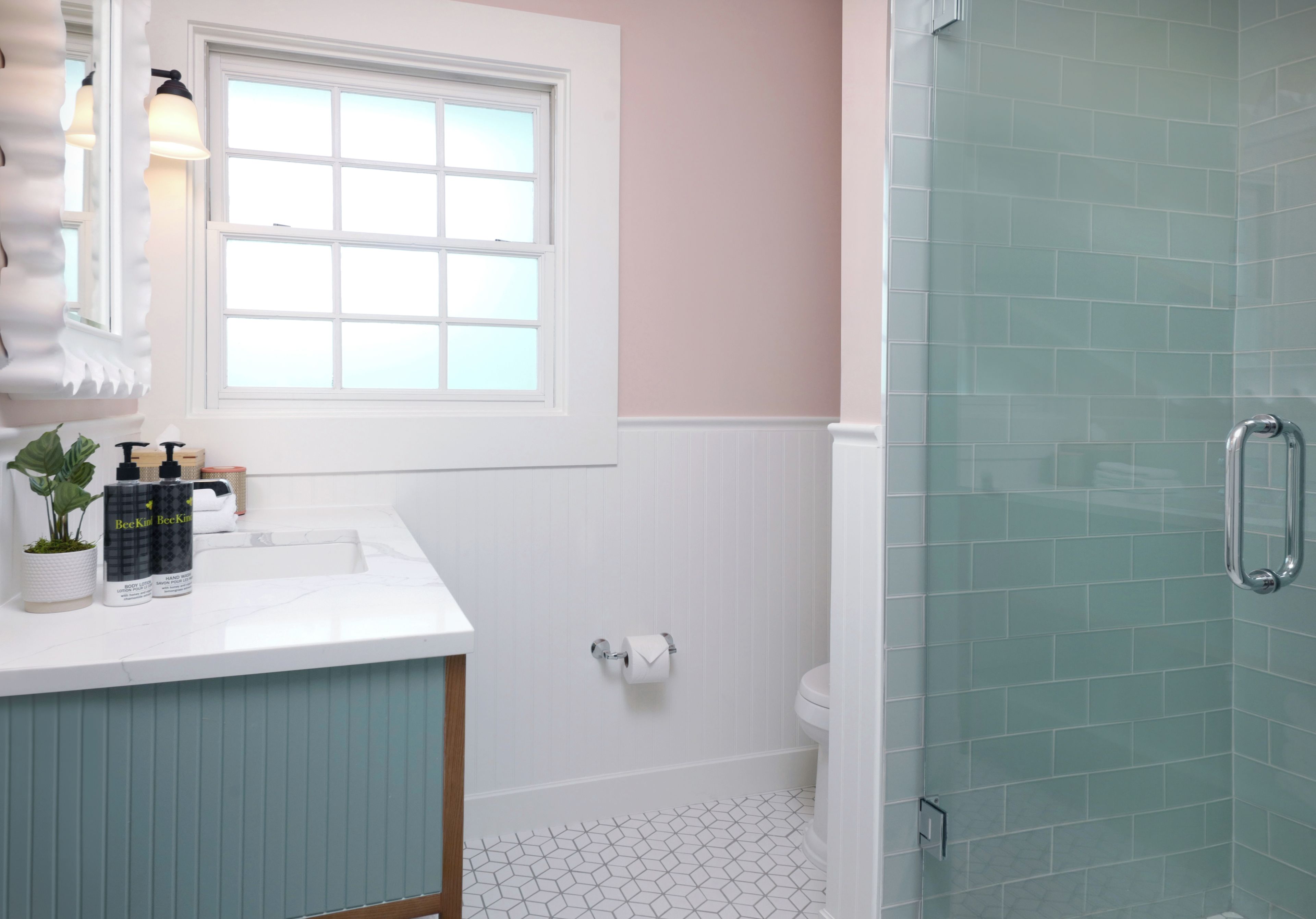 Un baño con lavamanos blanco, ventana, inodoro y zona de ducha.