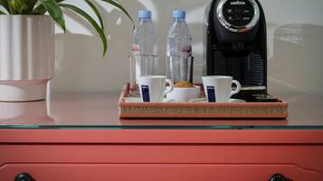 Ein Tablett mit Kaffeetassen, einer Wasserflasche und einer Kaffeemaschine auf einem Glastisch.