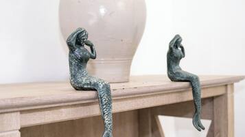 Dos esculturas de bronce sobre una mesa de madera, con un florero al fondo.