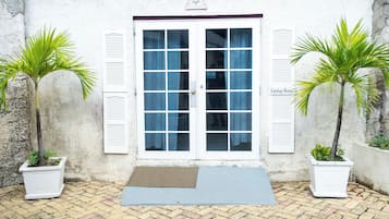 A building entrance with a double door, two potted palm trees, and a brick-paved ground.
