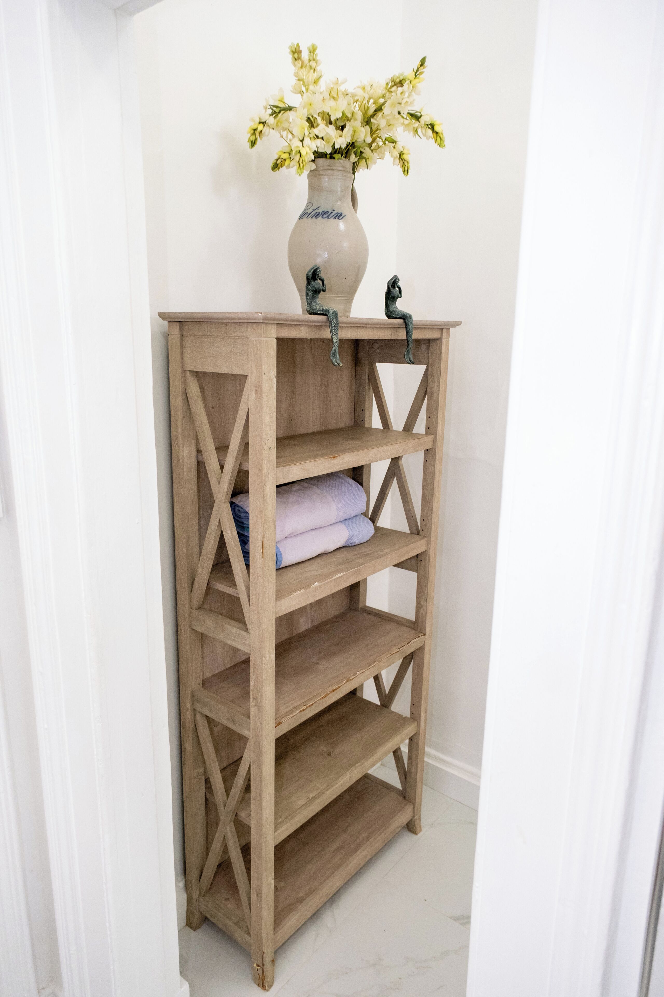 Una estantería de madera con un florero encima.