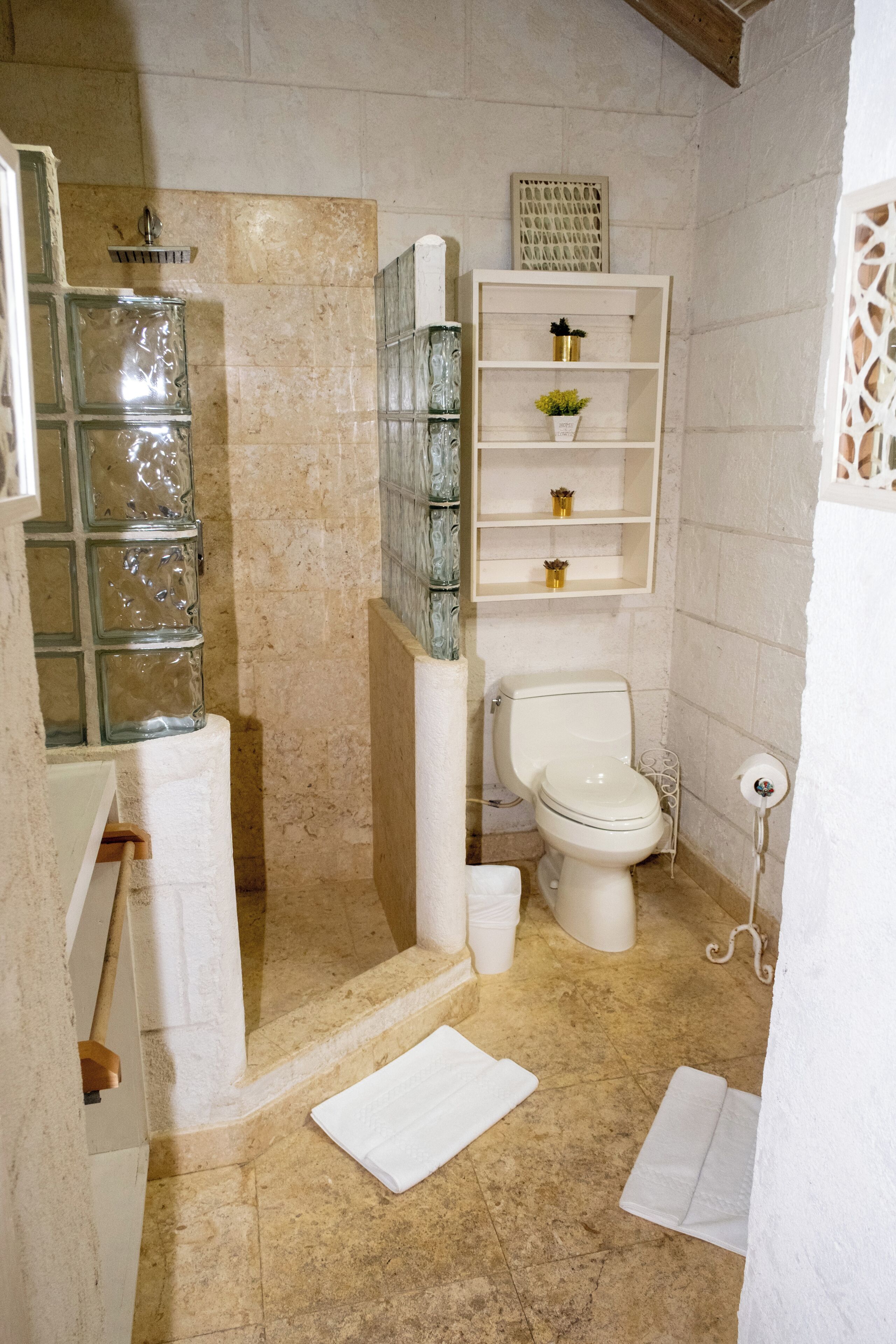 Een badkamer met een douchecabine van glas, een toilet en een plank met toiletartikelen.