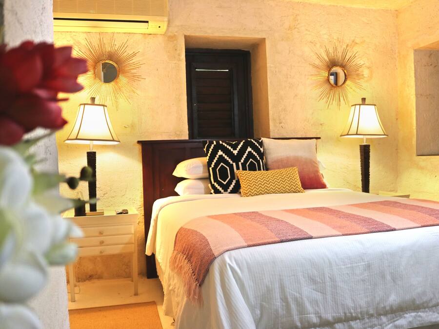 Un dormitorio con cama, dos mesitas de noche con lámparas, un espejo y una puerta.