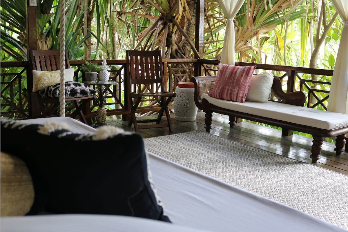 A wooden deck with a bed, a wooden chair, and a bench.