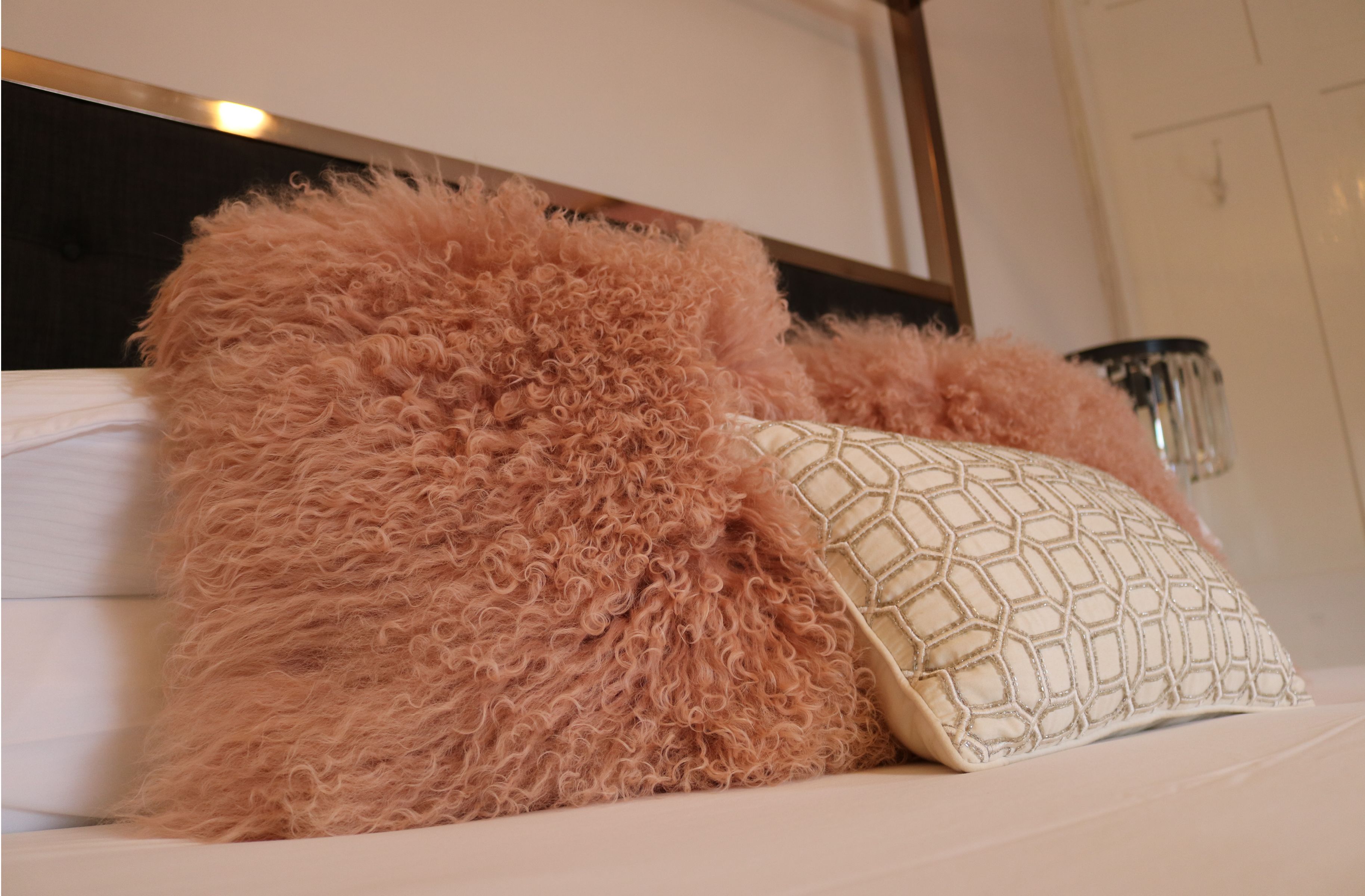Una cama con almohadas rosadas mullidas y una almohada estampada.