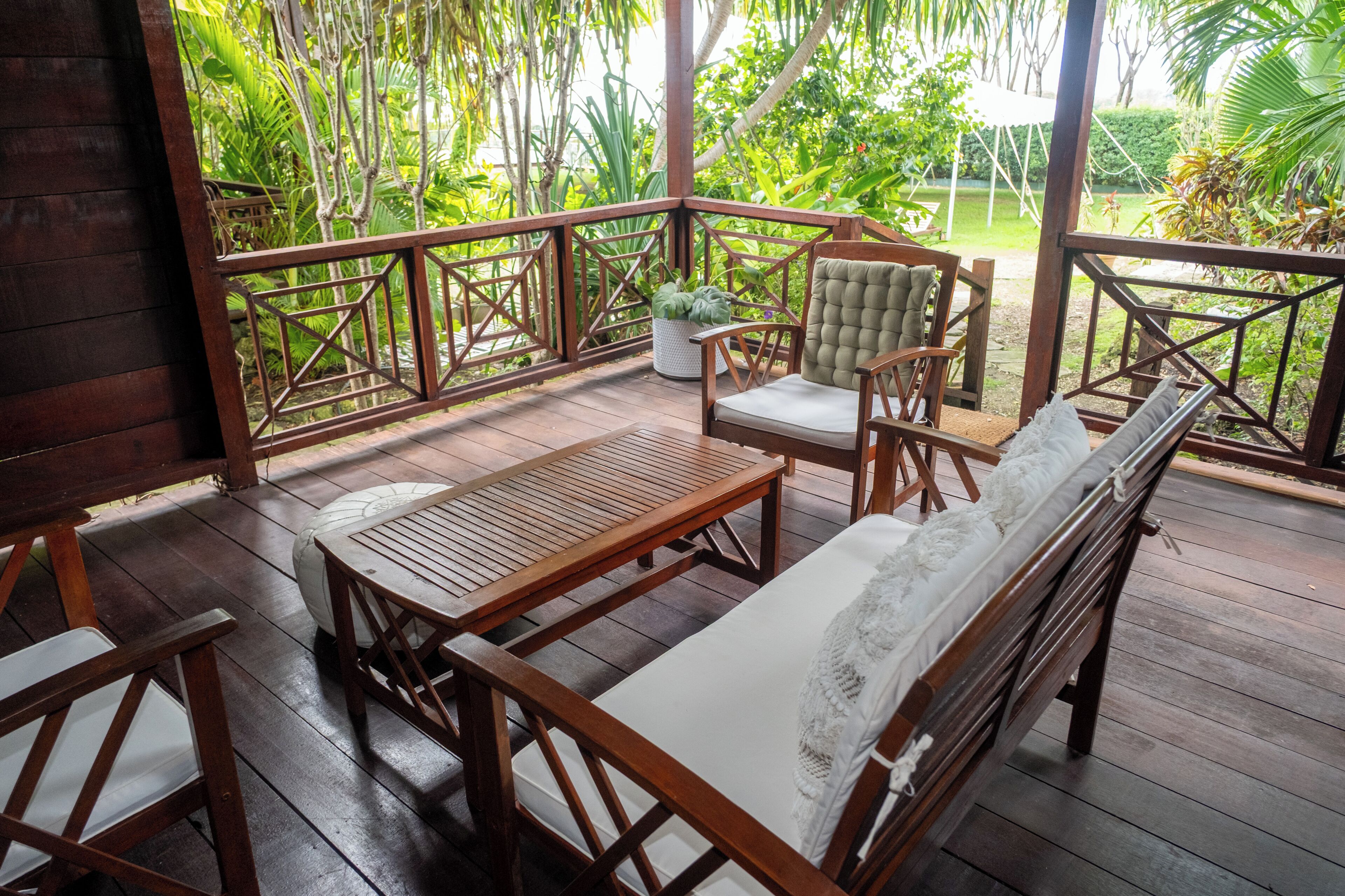 A wooden deck with a sofa, chairs, and a table, surrounded by a metal railing.