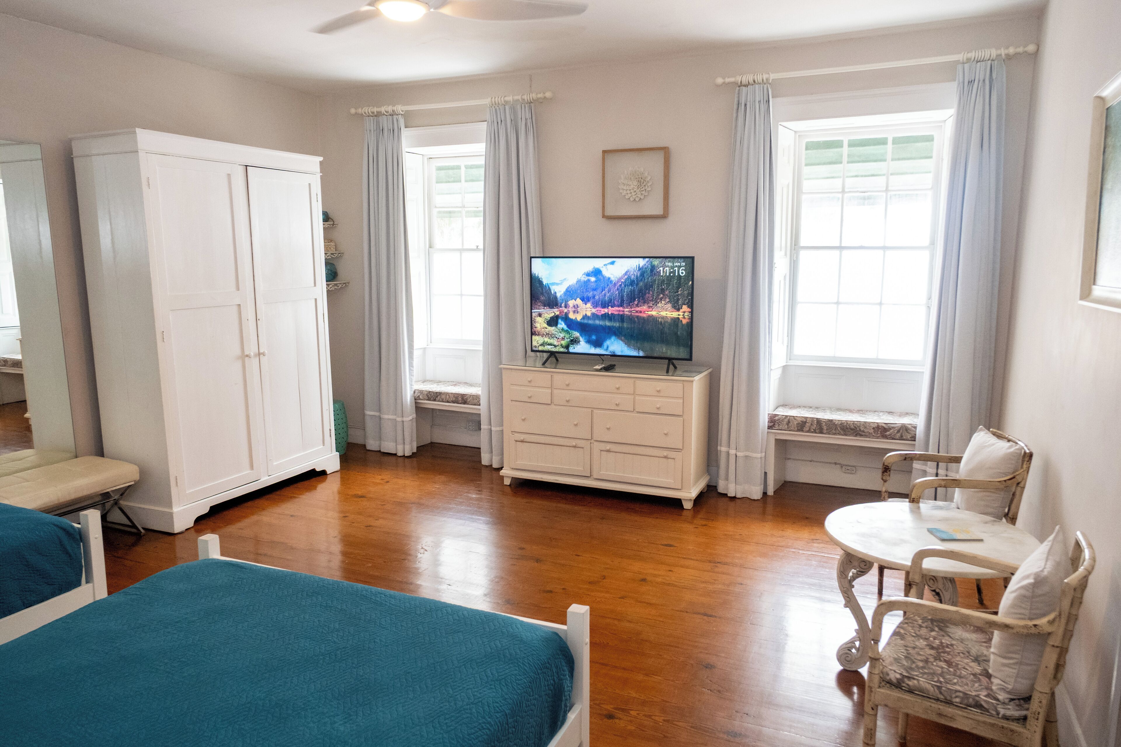 Una habitación con cama, sillón, televisor y armario.
