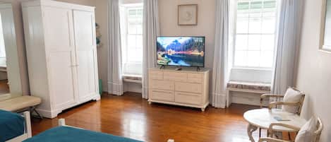 Una habitación con cama, sillón, televisor y armario.