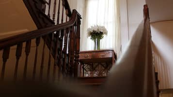 Una escalera de madera con un jarrón de flores blancas sobre una consola de madera.