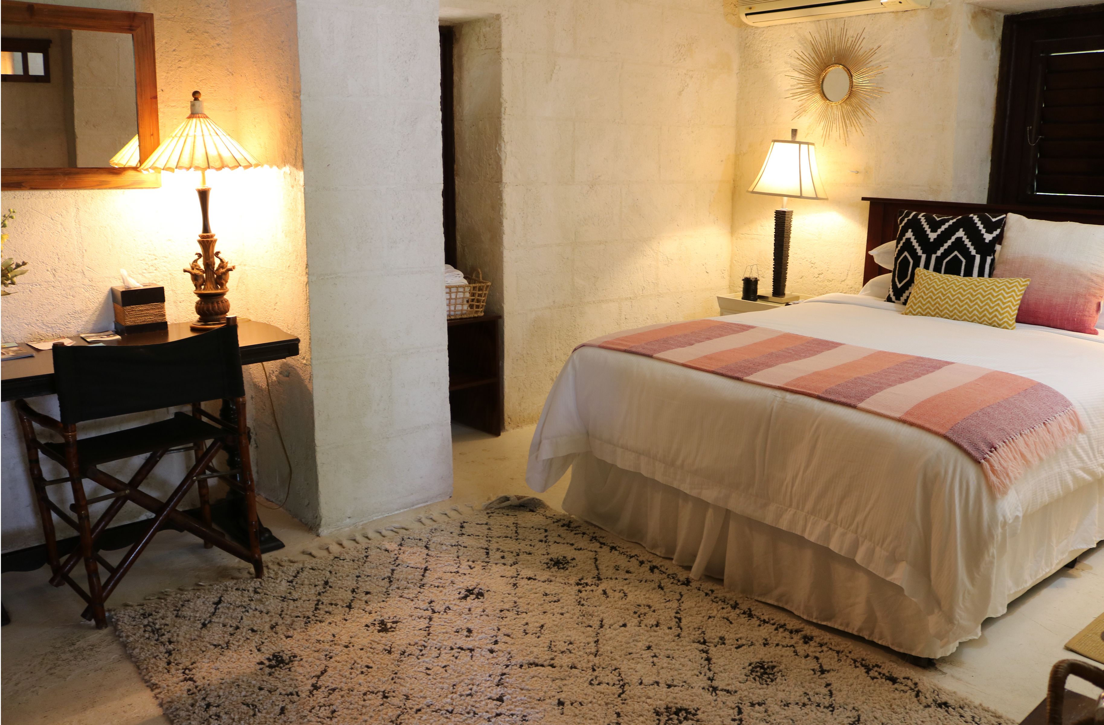 Un dormitorio ordenado con cama, lámparas de noche, un escritorio y una silla.