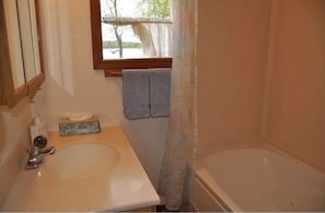 Un baño con lavamanos, ventana con vistas y bañera.