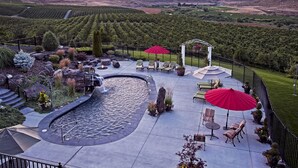 Une terrasse aménagée avec un jacuzzi, des sièges et une vue sur les vignes.