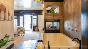 Une salle de bain moderne avec une grande baignoire, un porte-bougie en verre et une cheminée.