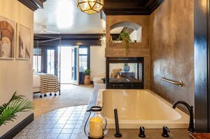 Un baño moderno con una bañera grande, un candelabro de vidrio y una chimenea.