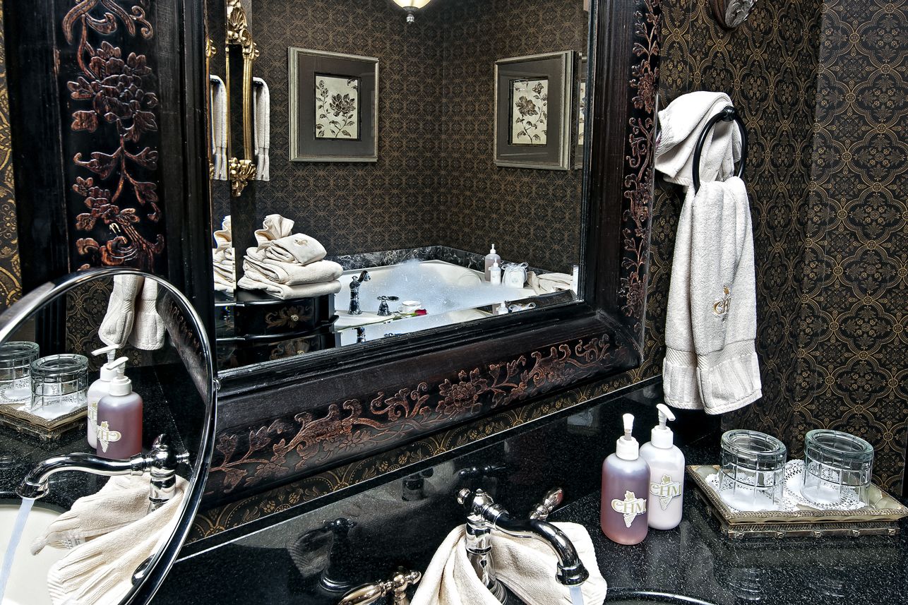 A bathroom with a large mirror, a bathtub, and a vanity with toiletries.