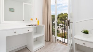 A modern bathroom with a large mirror, white cabinetry, and a view of the street through a glass door. - Hostal Talamanca (Santanyi)