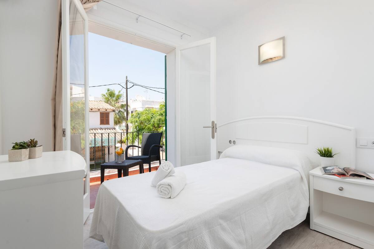 Ein Hotelzimmer mit einem Bett, einem Nachttisch, einem kleinen Tisch mit Stuhl und Blick auf den Balkon.