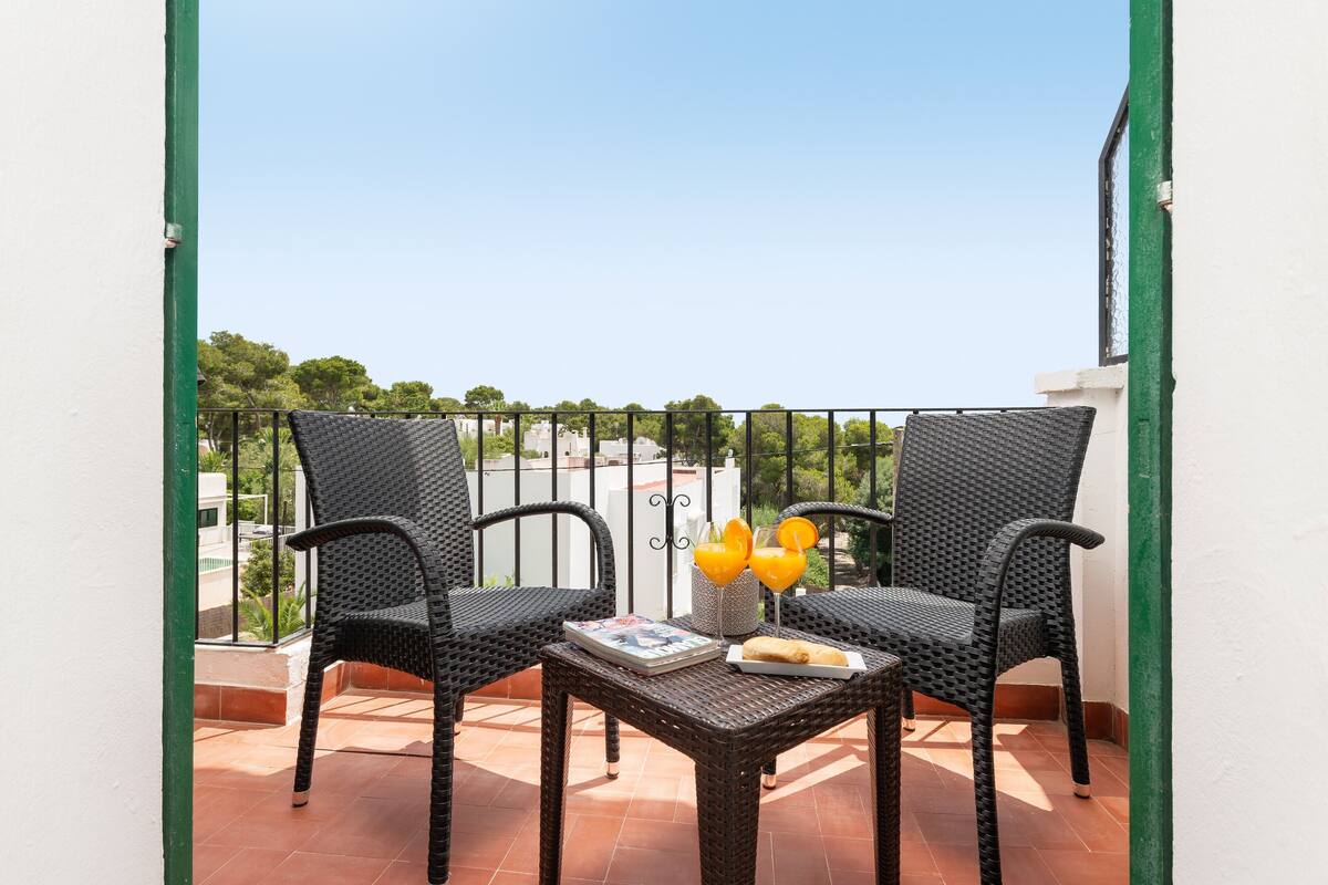 Ein Balkon mit zwei Korbstühlen, einem kleinen Tisch und einer Zeitschrift.