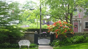 A pathway leading to a house with a stone wall, a white bench, and a gate. - Delano Homestead Bed & Breakfast (Fairhaven)