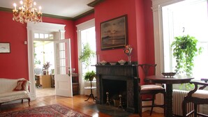 A room with a fireplace, a dining table, and a white sofa. - Delano Homestead Bed & Breakfast (Fairhaven)