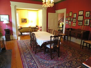 Une salle à manger avec une grande table, des chaises et un tapis à motifs.