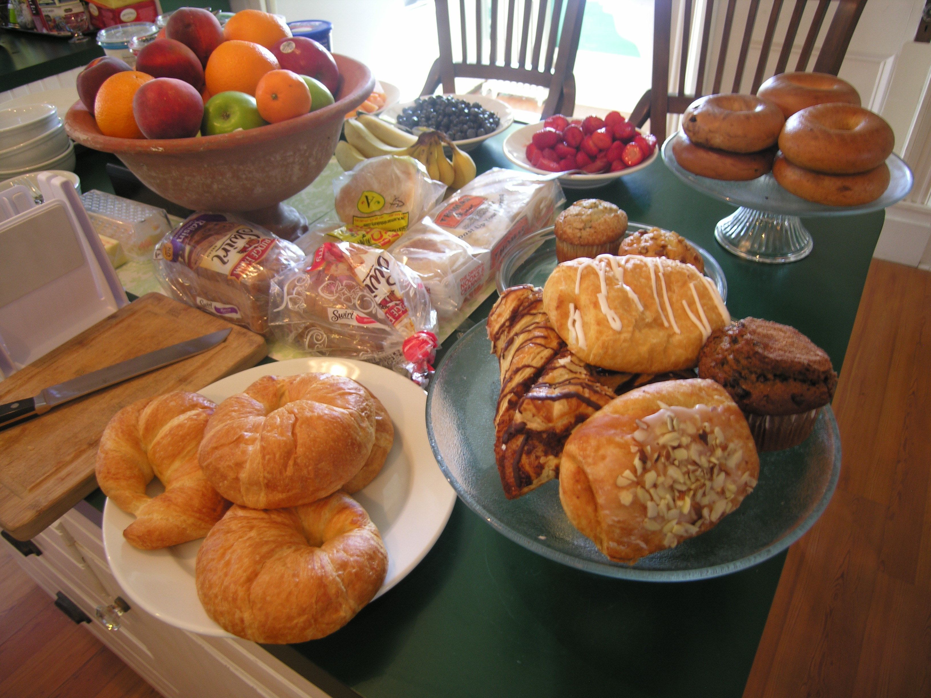 A table with various food items including fruits, pastries, and bread.