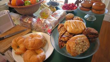 A table with various food items including fruits, pastries, and bread.