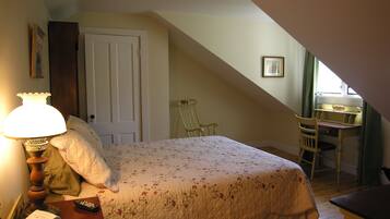A bedroom with a bed, a desk, a chair, a lamp, and a window.