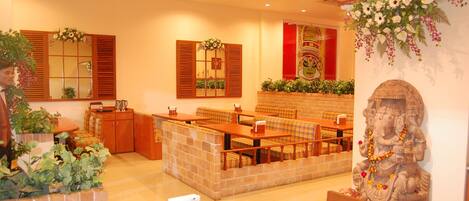 Un restaurante con muebles de madera, una barra de piedra y una estatua.
