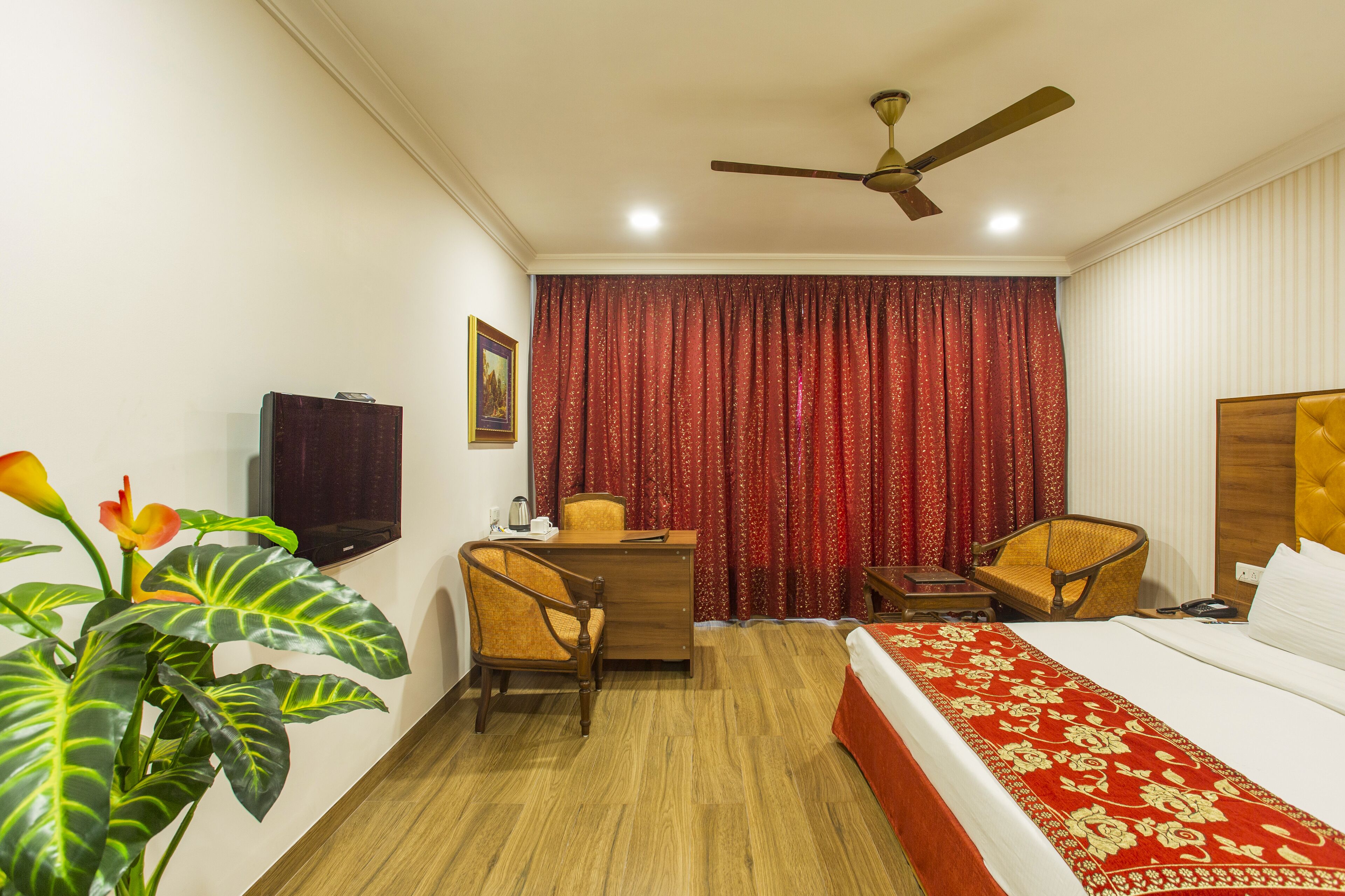 A hotel room with a bed, a desk, a chair, a television, and a ceiling fan.