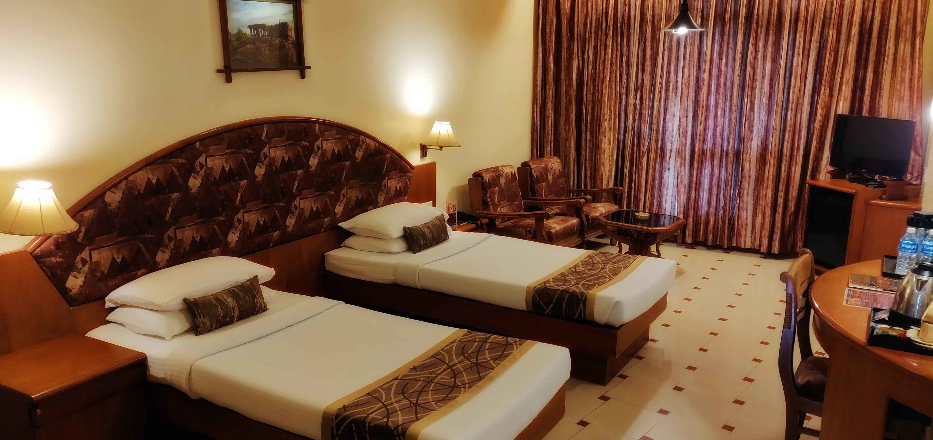 Een hotelkamer met twee bedden, een televisie, een bijzettafeltje en een stoel.