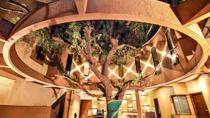 A tree wrapped in fabric, a staircase, and a reception area with chairs and a desk. - Hotel Malligi (Hospet)