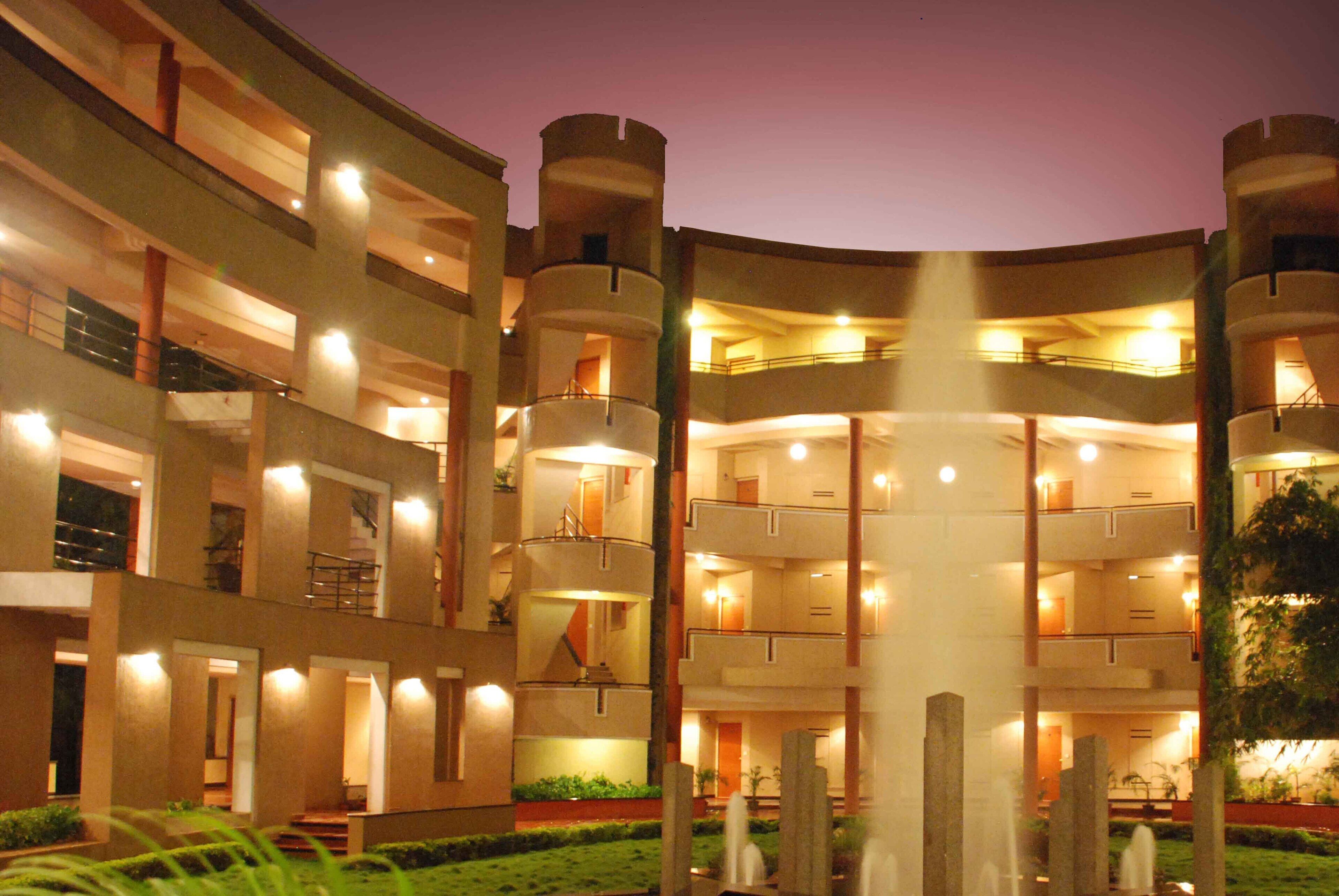 A multi-story hotel with a central courtyard, balconies, and illuminated windows.