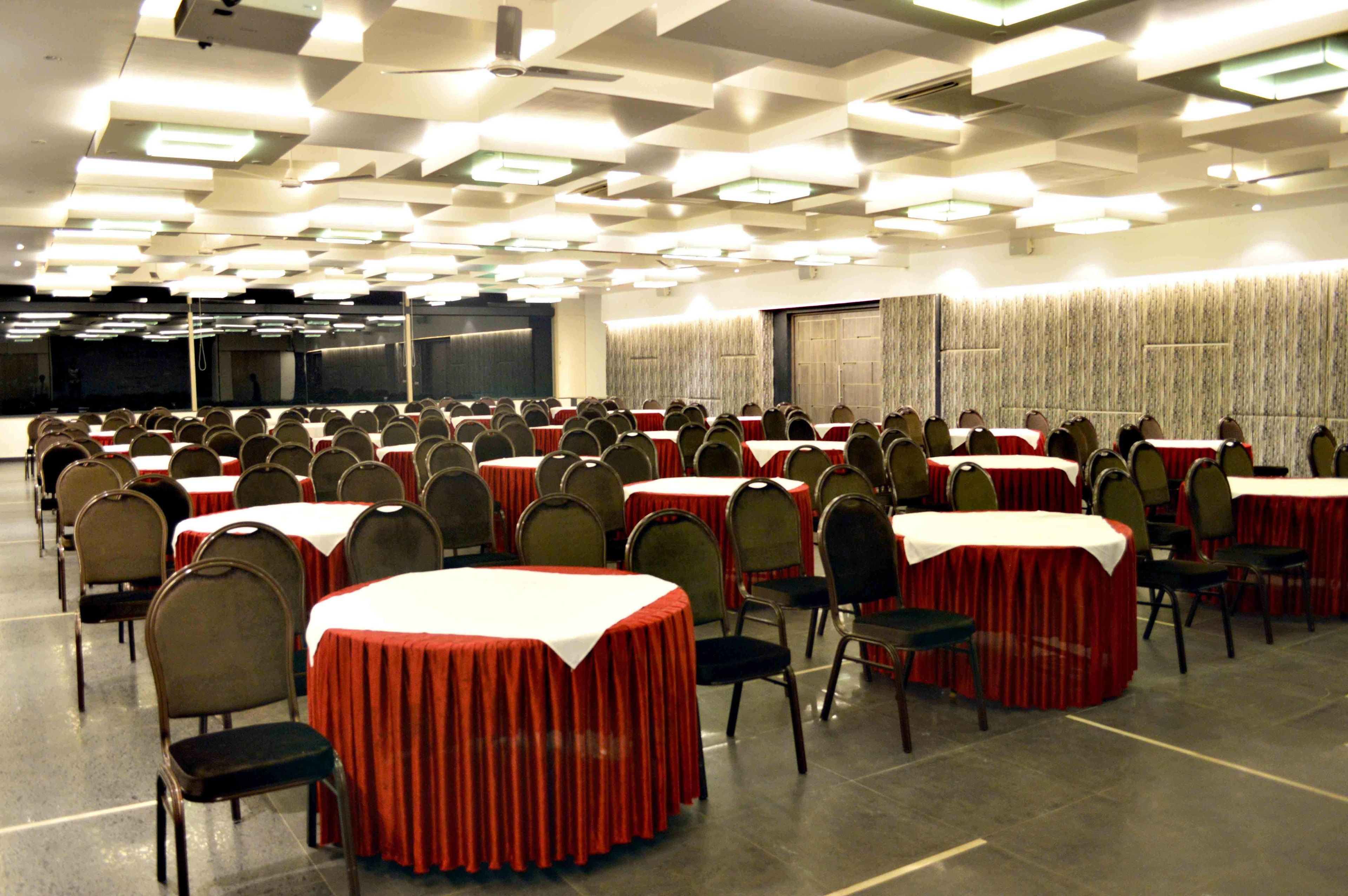 Un salón de conferencias con varias mesas y sillas dispuestas en filas.