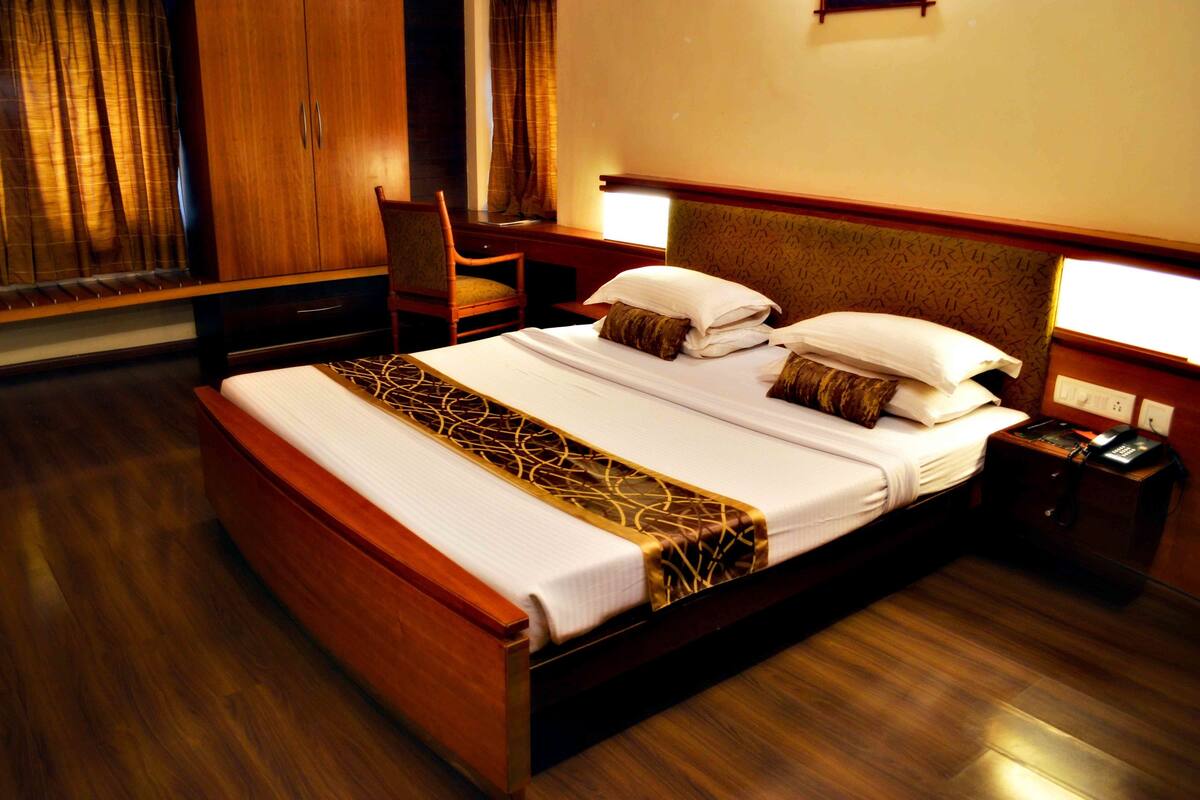 A hotel room with a wooden bed, a desk, and a chair.