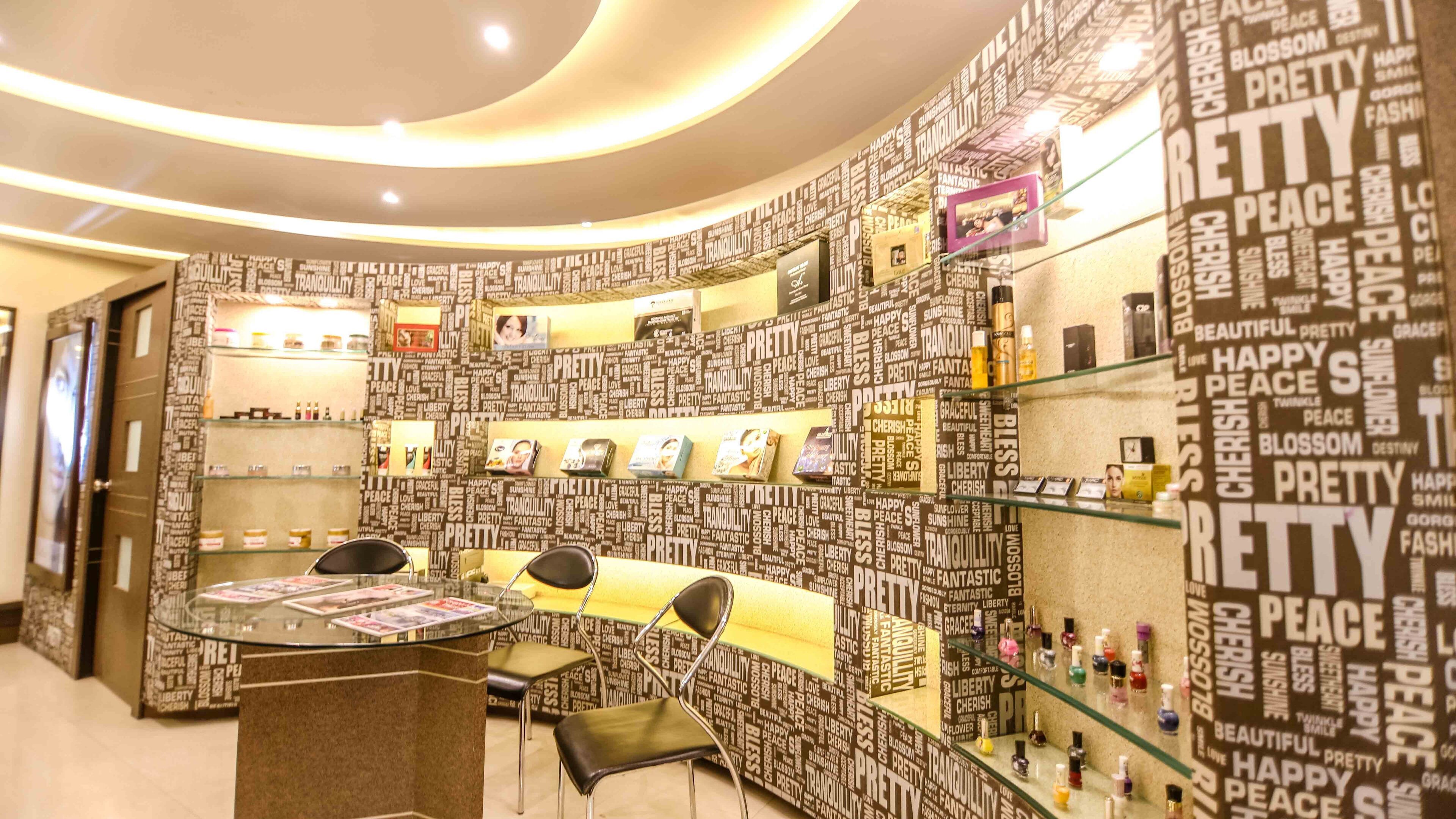 Un salón con una pared curva cubierta de palabras como “bonito”, “paz” y “tranquilidad”. Hay estanterías con productos y un mostrador de recepción con sillas.