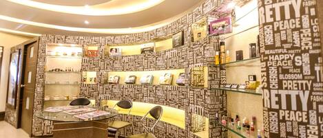 Un salón con una pared curva cubierta de palabras como “bonito”, “paz” y “tranquilidad”. Hay estanterías con productos y un mostrador de recepción con sillas.