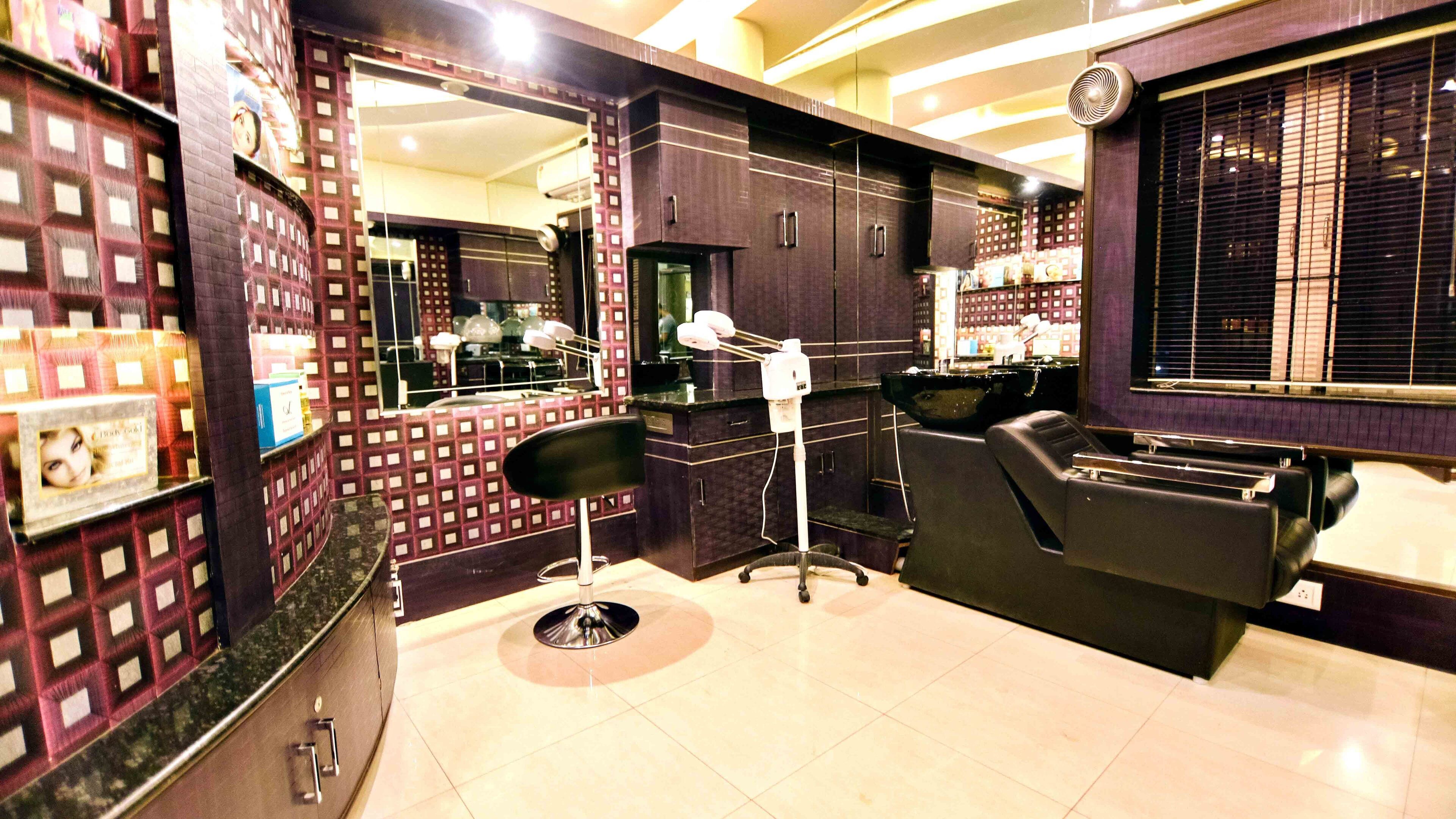 Un salón de belleza con una silla negra, un espejo y un lavamanos.