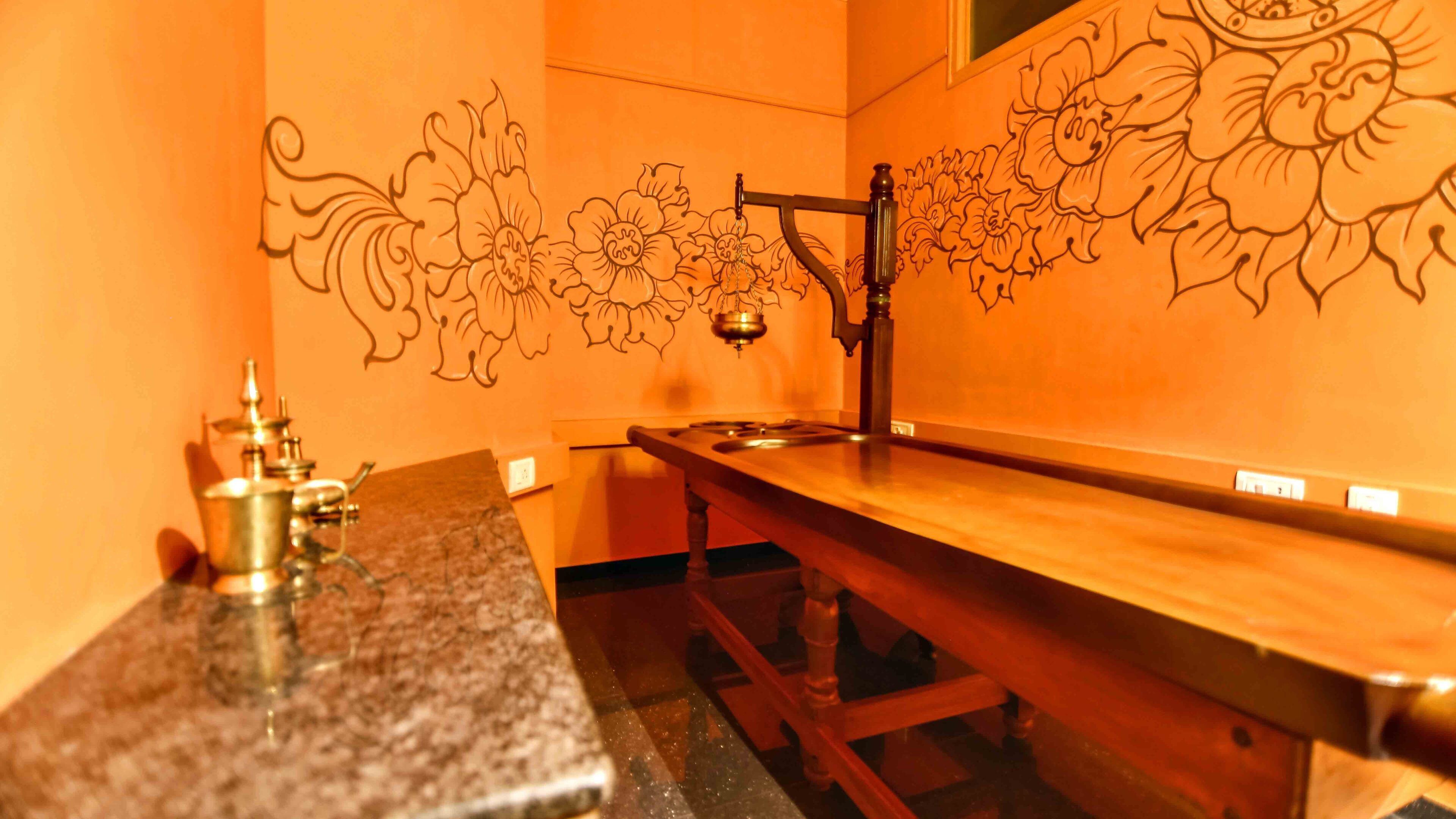 Un banc en bois, agrémenté d’un évier en métal et d’un mur décoratif orné de motifs floraux.